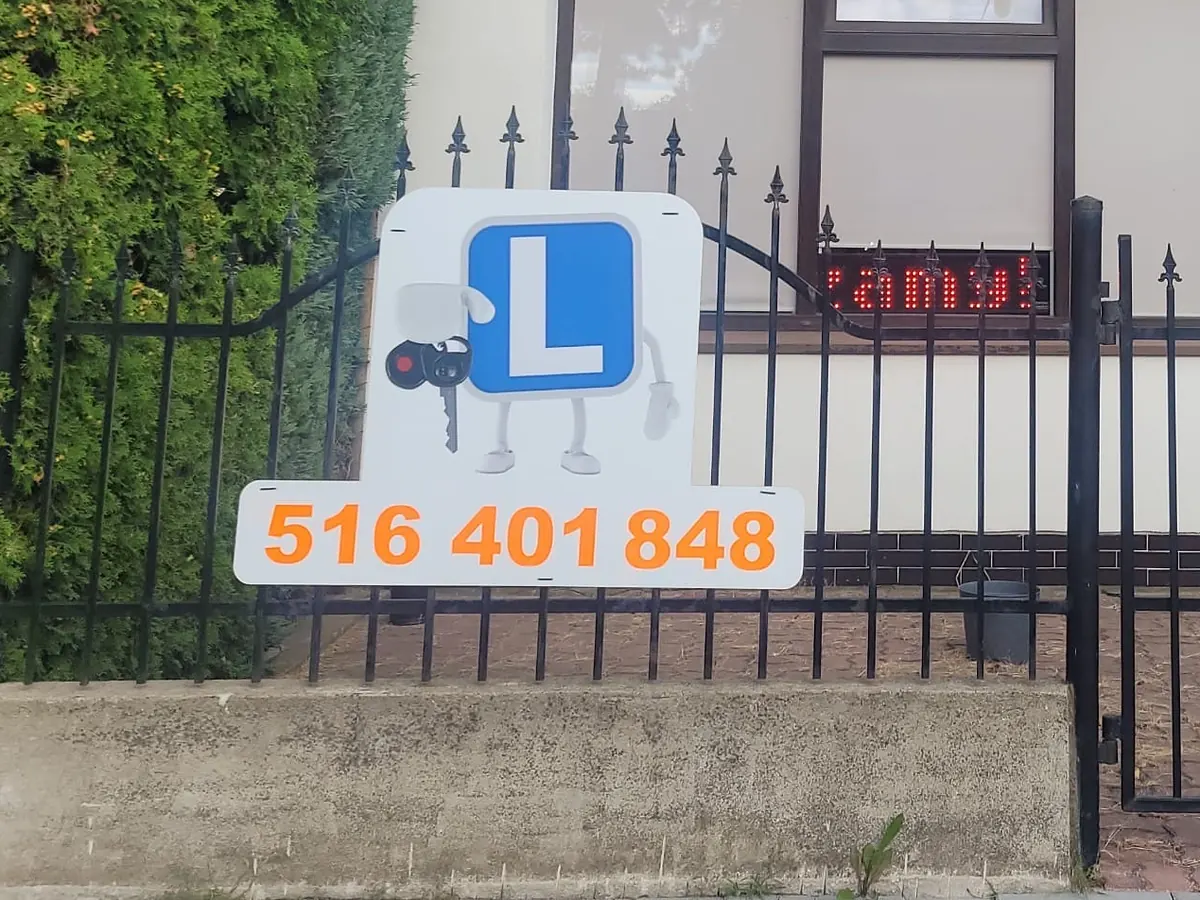 Tablica z literą L i numerem 516 401 848 przed biurem szkoły jazdy w Wołominie